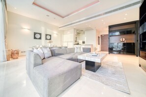 Een moderne woonkamer met een hoekbank, een salontafel en een keuken op de achtergrond.