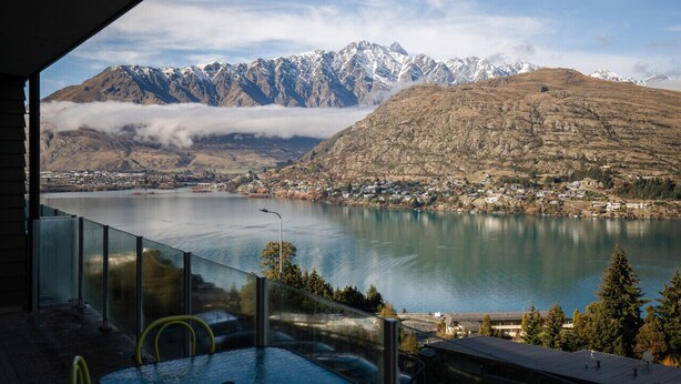 A lakeside view with mountains in the background, a clear sky, and a glimpse of a building with a balcony. - Top the Lake - Queenstown (Queenstown)