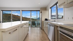 A modern kitchen with large windows, a dishwasher, and a view of mountains. - Top the Lake - Queenstown (Queenstown)