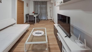A modern, minimalist living room with a sofa, a coffee table, a TV, and a dining area with a table and chairs. - Awesome apartment in Torrevieja (Torrevieja)