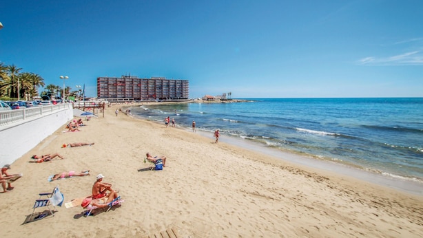 A beach with a large hotel in the background. - Awesome apartment in Torrevieja (Torrevieja)