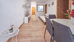 A narrow hallway with a wooden floor, a small table with a plant, a white sofa, and a dining table with chairs. - Awesome apartment in Torrevieja (Torrevieja)