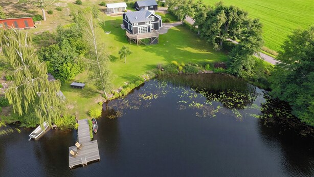 Propiedad frente al lago con casa, muelle y vegetación circundante.