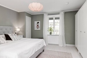 A bedroom with a bed, nightstands, a window with curtains, a potted plant, and a wall-mounted light fixture. - Schönes Haus mit Privatem Zugang zum See Hjorten Zwischen Vimmerby und Västervik (Hjorted)