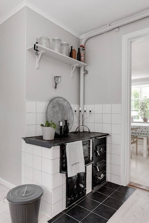 A kitchen with white tiles, a black countertop, a stove, and a trash bin. - Schönes Haus mit Privatem Zugang zum See Hjorten Zwischen Vimmerby und Västervik (Hjorted)