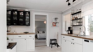 Una cocina moderna con armarios blancos, encimera de madera y un mueble negro con puertas de cristal.