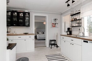 Una cocina moderna con armarios blancos, encimera de madera y un mueble negro con puertas de cristal.
