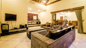 A spacious living area with a large sofa, a flat-screen TV, and a dining area with chairs and a table. - Luxury Private Villa in Heart of Seminyak (Seminyak)