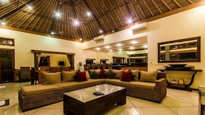 A spacious living area with a large sectional sofa, a coffee table, and a high ceiling with a thatched roof. - Luxury Private Villa in Heart of Seminyak (Seminyak)