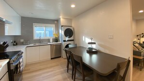 A modern kitchen with a built-in oven, a dishwasher, and a window above the sink. - Elegant Beachside 2B1B Retreat • Newly Renovated • Free Parking • 15min SF/SFO (Pacifica)