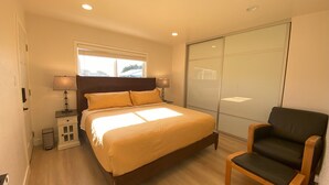 A bedroom with a bed, bedside lamps, a chair, a wardrobe, and a window. - Elegant Beachside 2B1B Retreat • Newly Renovated • Free Parking • 15min SF/SFO (Pacifica)