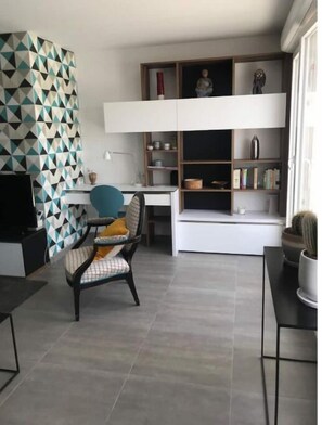 Cozy living space with a geometric-patterned wall, comfortable seating area, and bookshelf.