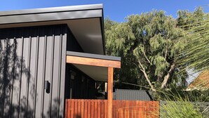 A modern building with a grey facade, a wooden deck, and a fence. - Quedji Cottage - Beautiful 2 bed private cottage 3 min walk to Dunsborough town. (Dunsborough)
