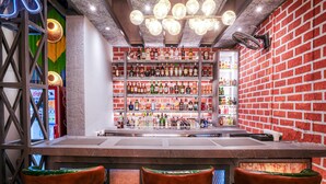 Un espace bar avec un mur en briques, des étagères remplies de bouteilles d’alcool et un panneau lumineux au néon.