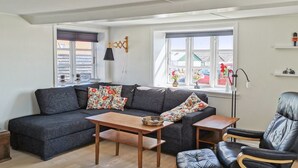 A modern living room with a grey sofa, wooden coffee table, and a black leather chair.