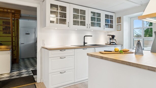 A modern kitchen with white cabinetry, a black faucet, and a wooden countertop.