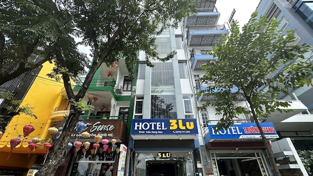 Un edificio de varios pisos con un llamativo letrero que dice 'HOTEL 3LU'.