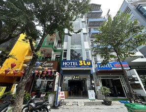 Un immeuble à plusieurs étages, sur lequel on peut voir une grande enseigne indiquant « HÔTEL 3LU ».