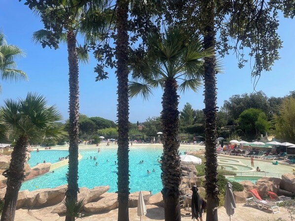A pool area with palm trees, lounge chairs, and a clear blue sky.