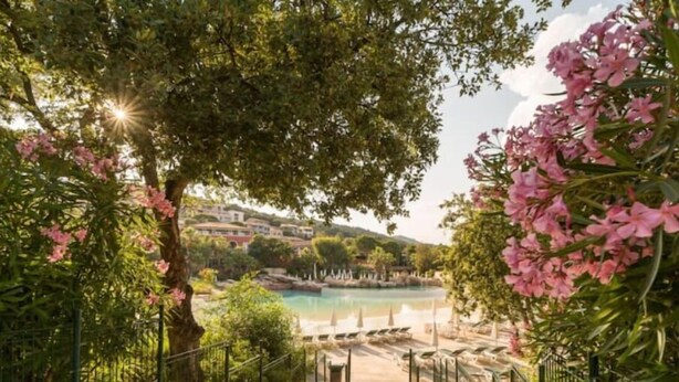 A pathway leading to a pool with a view of a hillside and buildings in the background.
