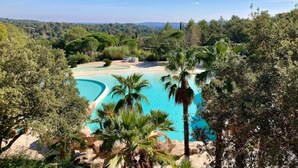 A pool surrounded by lush greenery and trees, with a clear blue sky above.