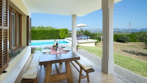 A patio with a pool, wooden furniture, and a view of the landscape. - VILLA GABRIEL - RUSTIC STAY (Alcúdia)