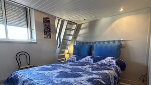 Un dormitorio con una cama, una silla, una ventana con persianas, una escalera y un cartel en la pared.