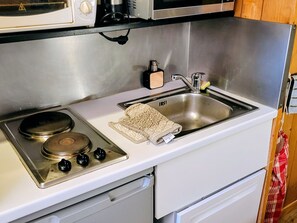 A kitchen with a stove, sink, and microwave.