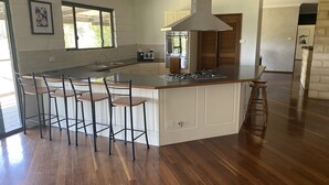 Una cocina moderna con una isla central, taburetes de bar, un ventanal grande y un horno empotrado.