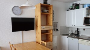 A compact kitchen with white cabinets, a wooden table, and a built-in microwave. - Cozy studio 4 pax · Balcony · Wifi · Pets allowed (Tignes)