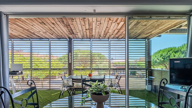 A modern outdoor patio with a glass table, chairs, and a TV. - Biscarrosse beach, air-conditioned apartment with wifi, center, 4 pax (Biscarrosse Plage)