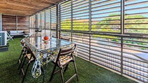 A dining area with a glass table, chairs, and a view of vineyards through metal bars. - Biscarrosse beach, air-conditioned apartment with wifi, center, 4 pax (Biscarrosse Plage)
