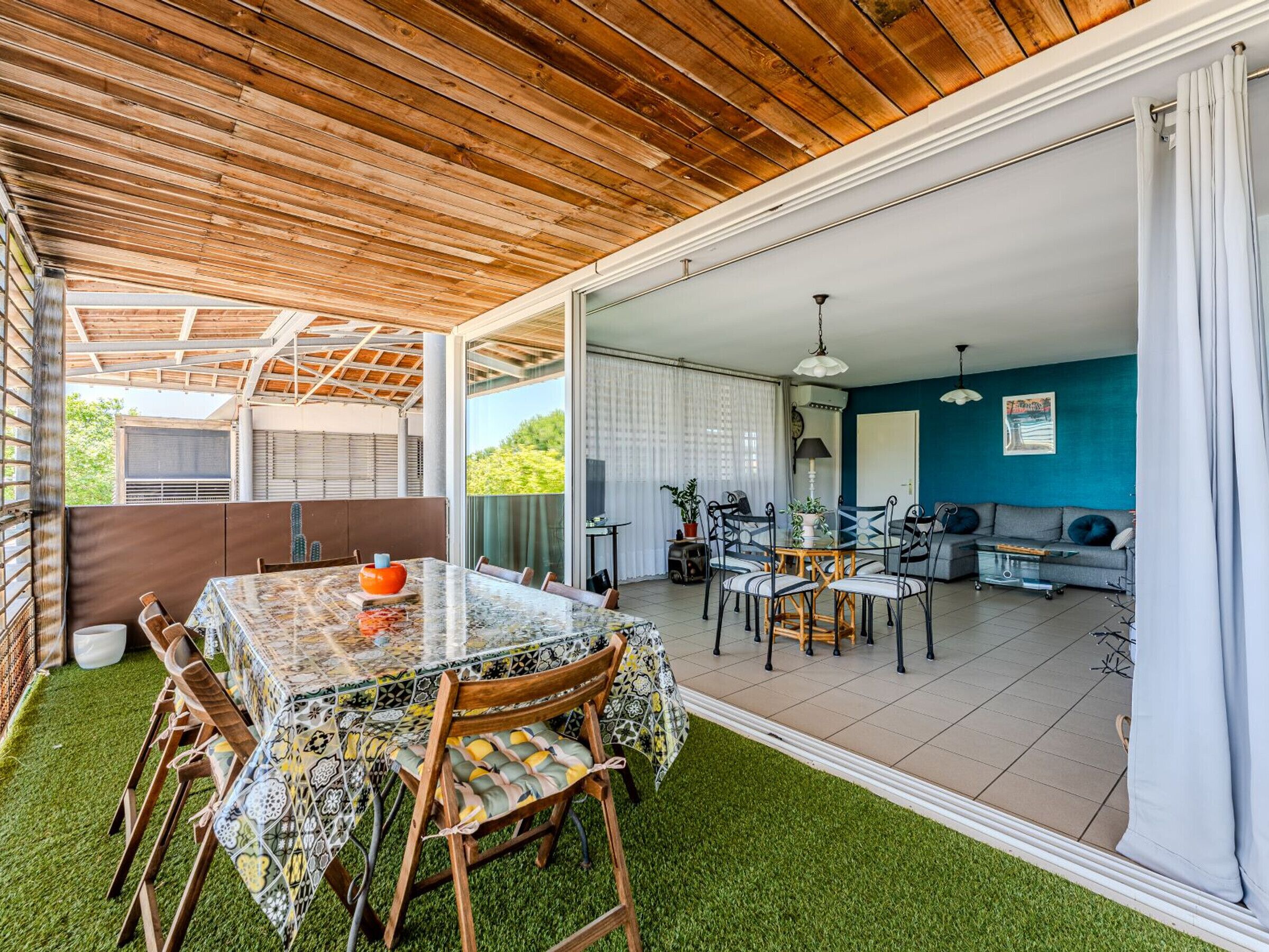 Un patio amplio con mesa y sillas para comer, un conjunto de sofás y vistas al jardín.