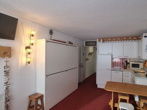 A compact kitchen with a refrigerator, microwave, and wooden table. - Comfortable studio, ski-in/ski-out, south-facing balcony (Plagne Aime 2000)