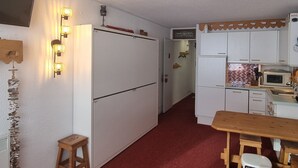 Eine kleine Küche mit Kühlschrank, Mikrowelle und Holztisch.
