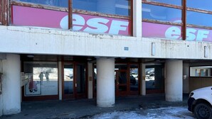 A building with a large sign reading "ESF" and a sign below it that says "LE CERVIN". There are glass doors and a parking area in front.