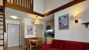 A compact living space with a dining area, kitchenette, and a red sofa.