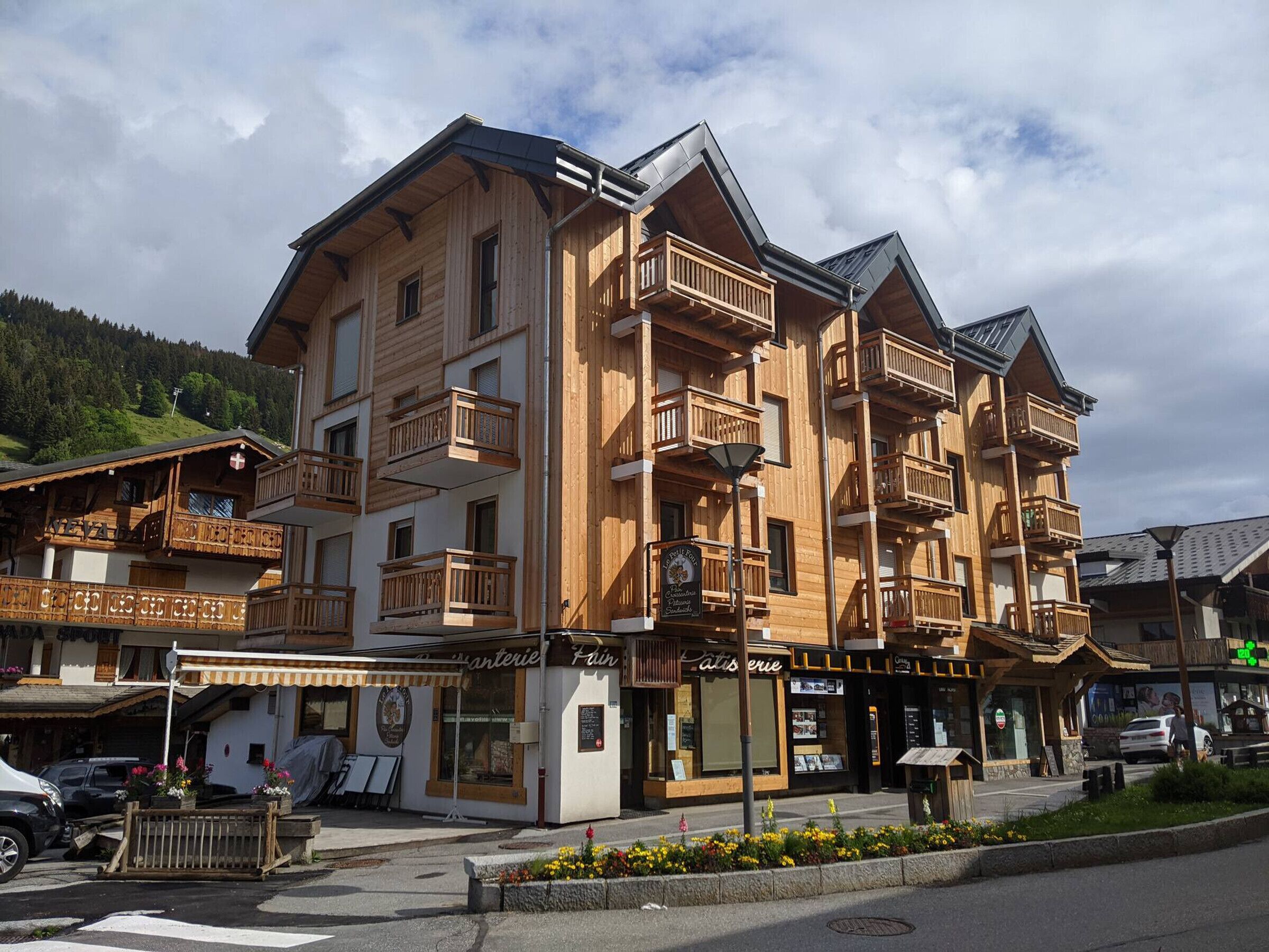 Un immeuble en bois à plusieurs étages, doté de balcons, d’un café et d’un restaurant situés au rez-de-chaussée.