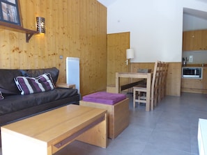 A compact living space with a sofa, a small dining table, and a kitchenette area. - 4-room duplex - Ski-in/Ski-out with Parking (La Plagne Montchavin Les Coches)