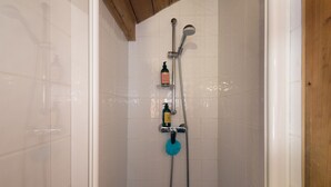 Une douche équipée d’un pommeau de douche à main, d’un robinet mural et d’un distributeur de savon.