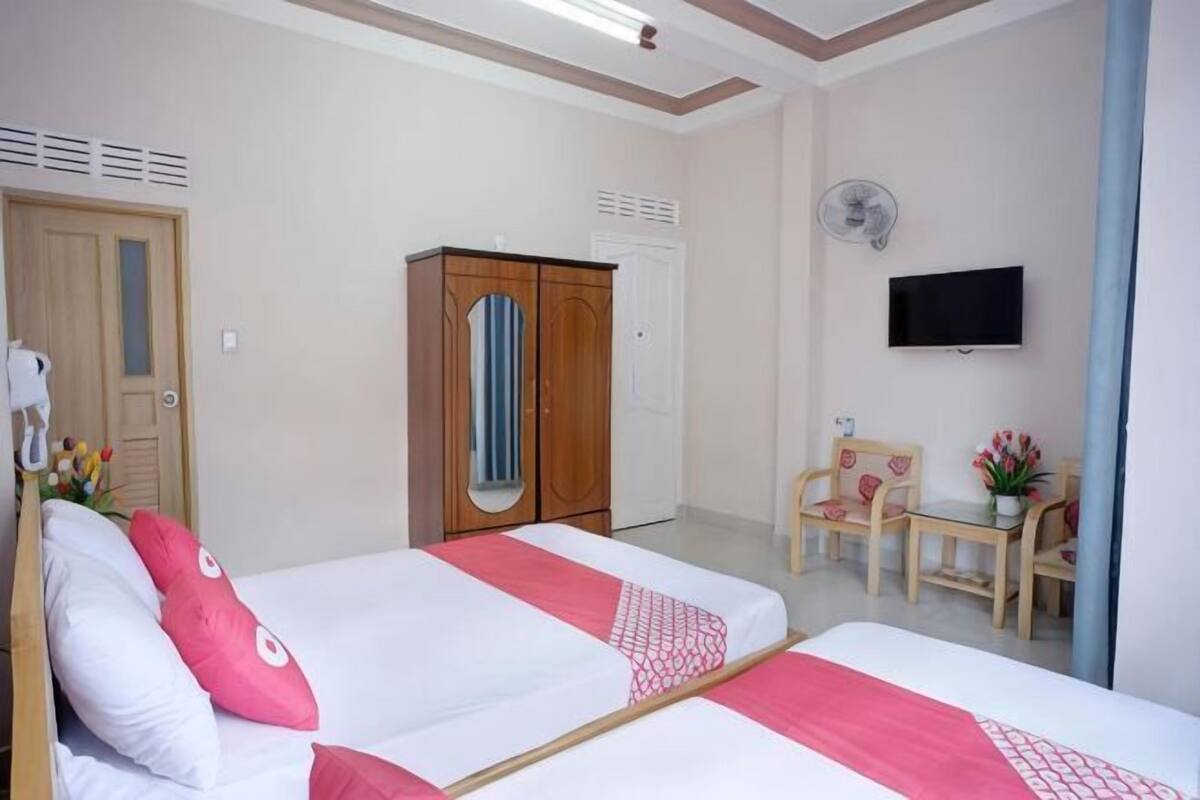 A hotel room with two beds, a TV, a wardrobe, a desk, and a chair.