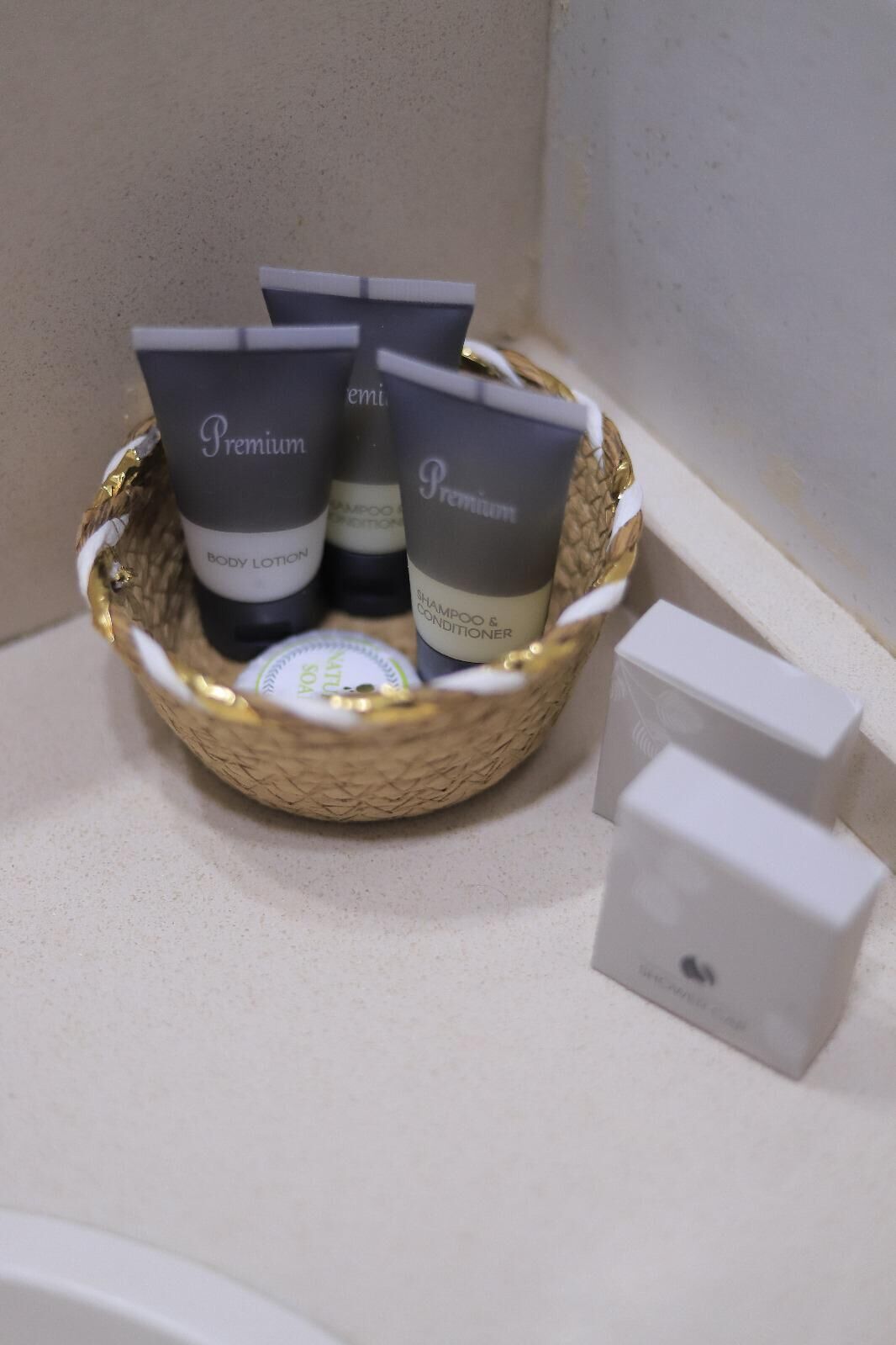 Manden met vier flessen Premium body lotion en shampoo en conditioner, geplaatst op een aanrecht naast een witte doos.