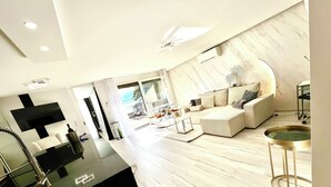 A modern living room with a sofa, a coffee table, and a TV mounted on the wall. - Ideal Lakeside Retreat: 2-bedroom Spa ap. With Lake View, Centre, Sleeps 1-4 (Montreux)