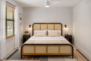 A bedroom with a bed, two bedside tables, a ceiling fan, and a window with blinds. - Luxury Oasis: Pool, Hot Tub, Games + Guesthouse (Manor)