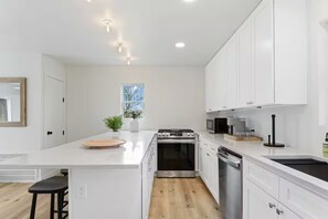 A modern kitchen with white cabinetry, a central island, and built-in appliances.