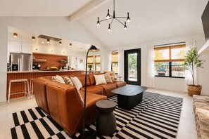 A modern kitchen with a built-in oven, a dining area with a black and white striped rug, and a large window with a view of the outdoors. - Luxury Oasis: Pool, Hot Tub, Games + Guesthouse (Manor)
