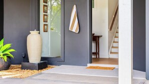A modern entrance with a large mirror, a potted plant, and a doormat. - "Sunset Valley Views" – Close to Beach (Avoca Beach)
