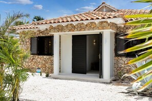A house with a stone facade, a tiled roof, and a gravel driveway.