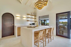 A modern kitchen with a central island, bar stools, and a large window.