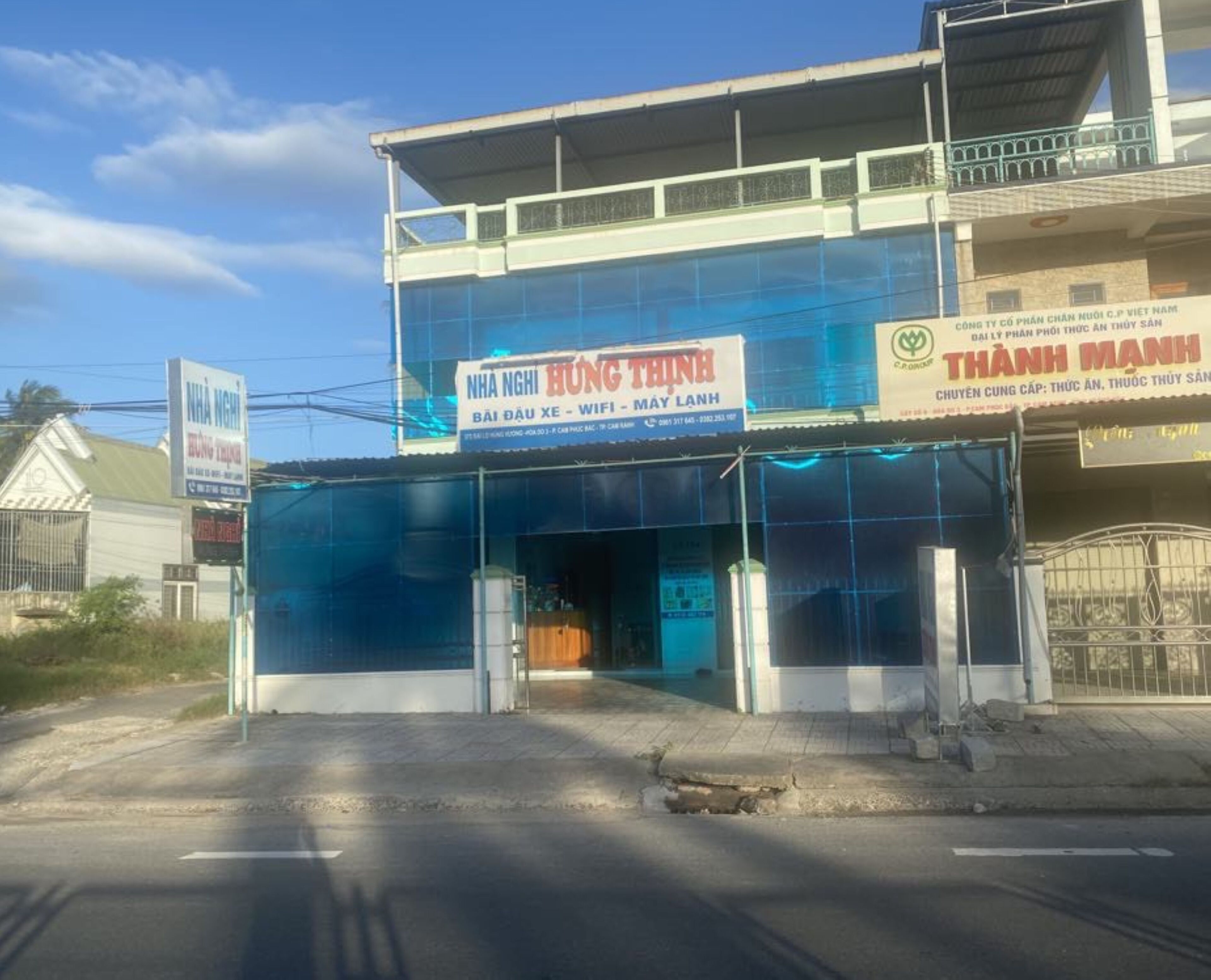 A two-story building with a blue facade and signage for 'NHA NGHI HUNG THINH' offering WiFi and a Mayan restaurant.
